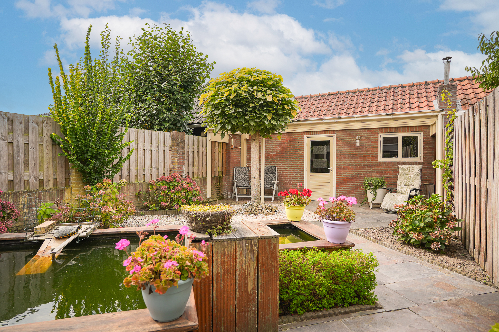 Aangelegde tuin met vijver en borders bij woning te koop in Drunen